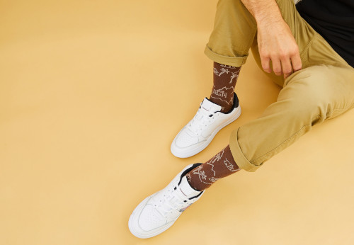 Homme assis avec des chaussures blanches et des chaussettes marron fantaisies